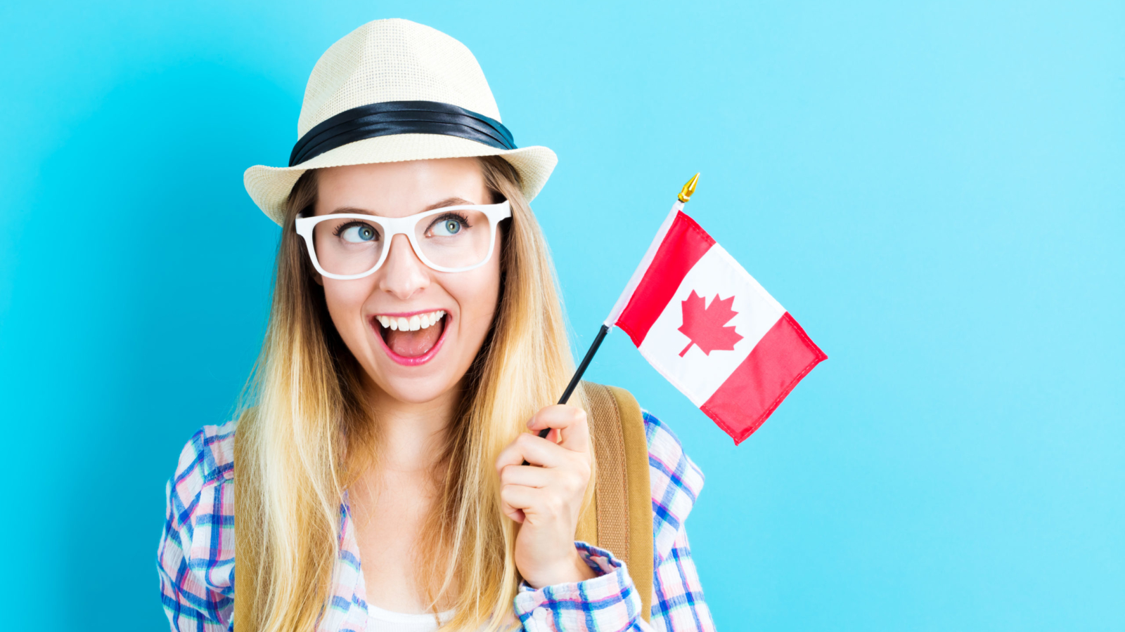 Happy young traveling woman holding Canadian flag
