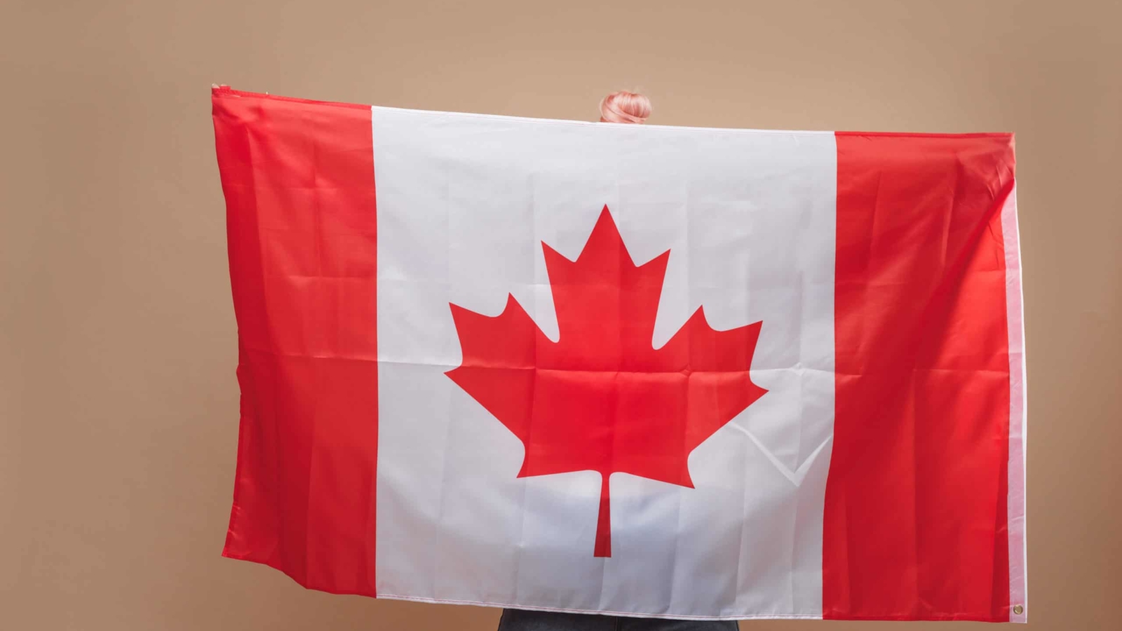 Beautiful blonde woman standing with Canadian flag